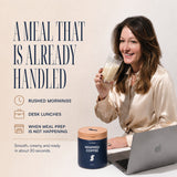 Woman enjoying Daily Shake Whipped Coffee as a convenient meal at her desk