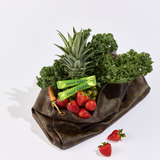 Fruits and vegetables in a reusable bag with 'Daily Greens' packaging on a white background