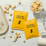 Two yellow 'Caramel Popcorn' packets on a marble surface with scattered popcorn.