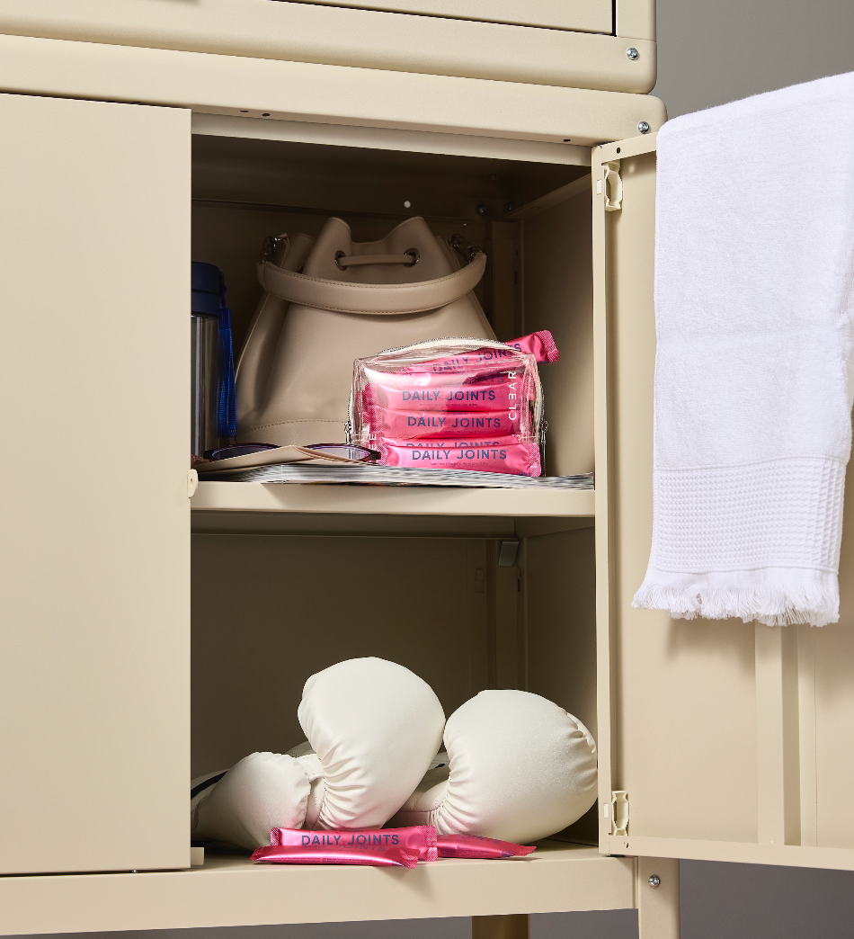 Beige locker with boxing gloves, pink bags, and a white towel inside.