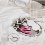 Tea set with newspaper and pink packets on a white surface