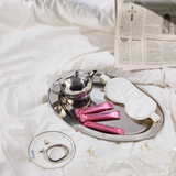 Tea set with newspaper and pink packets on a white surface