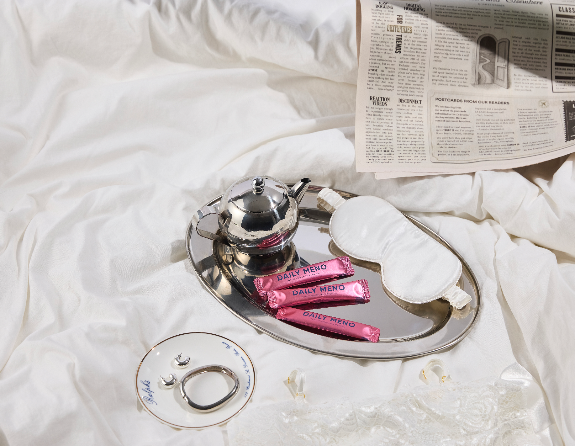 Tea set with newspaper and pink packets on a white surface