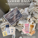 Goodie bags with Daily Wellness Club products and Ciroa Beauty shimmer sticks on a gray surface.